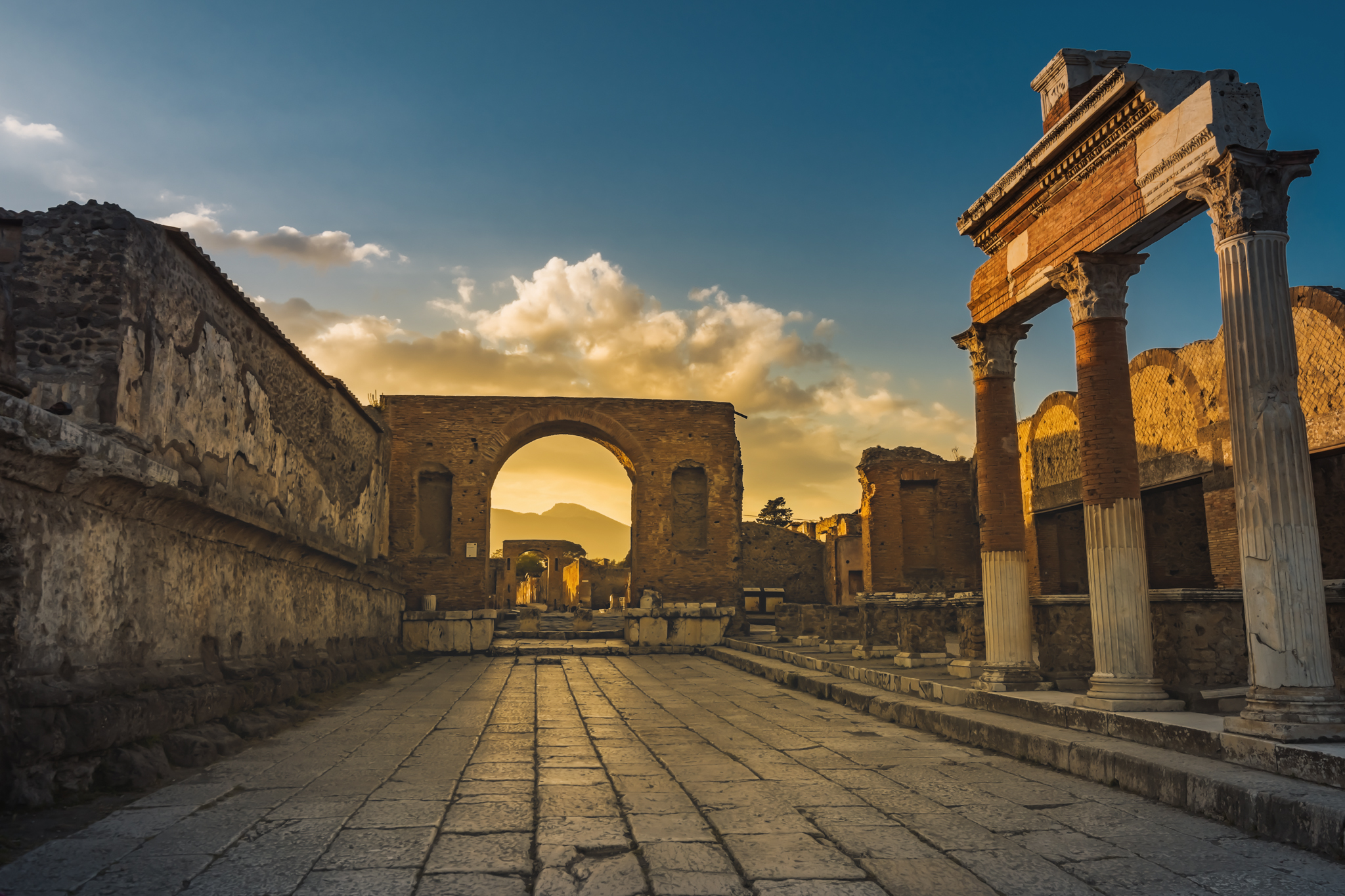 Ruins of ancient city of Pompeii, ancient roman city against Vesuvius volcano at sunset, Italy. Street in Pompeii